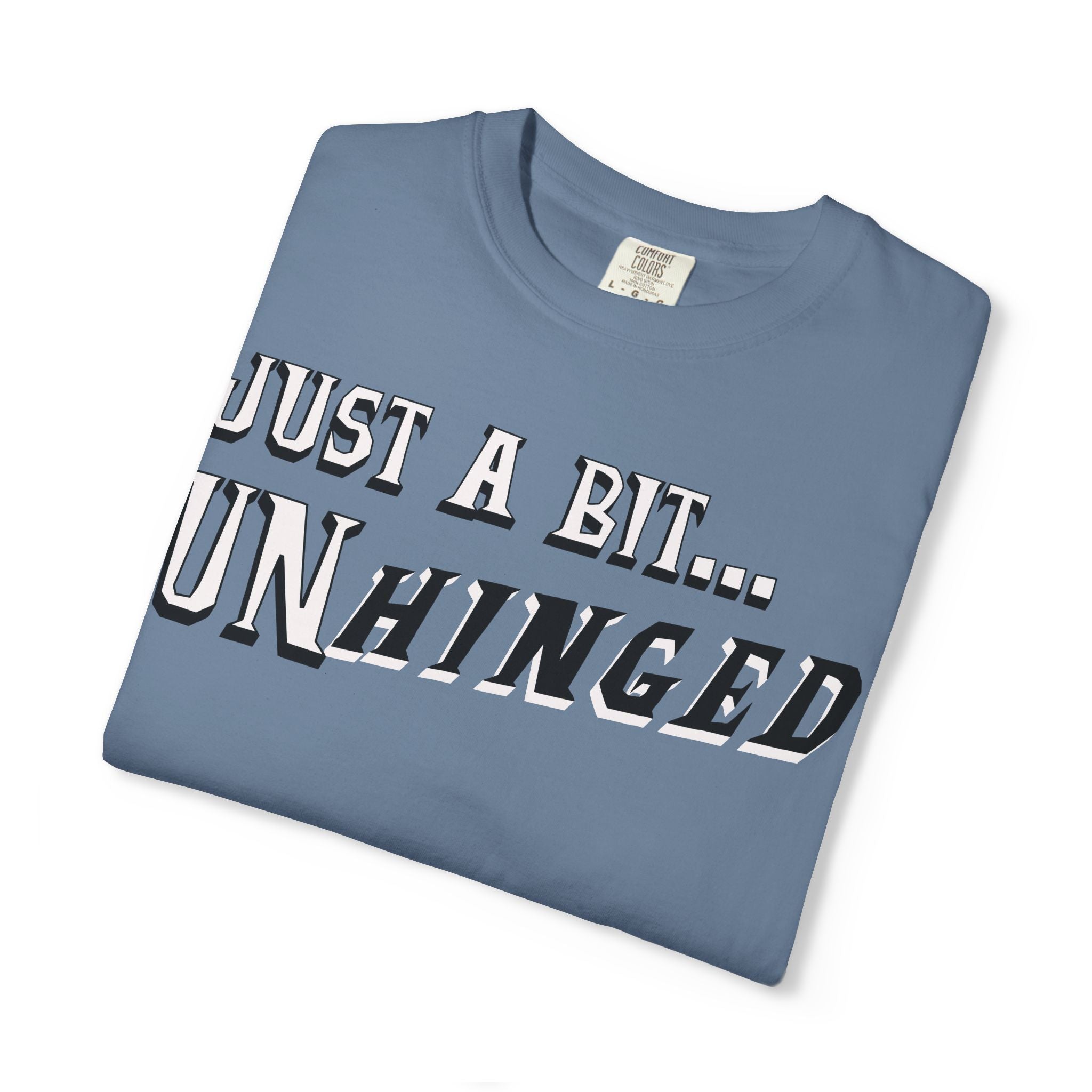 Folded blue t-shirt with text 'JUST A BIT... UNHINGED' on a white background