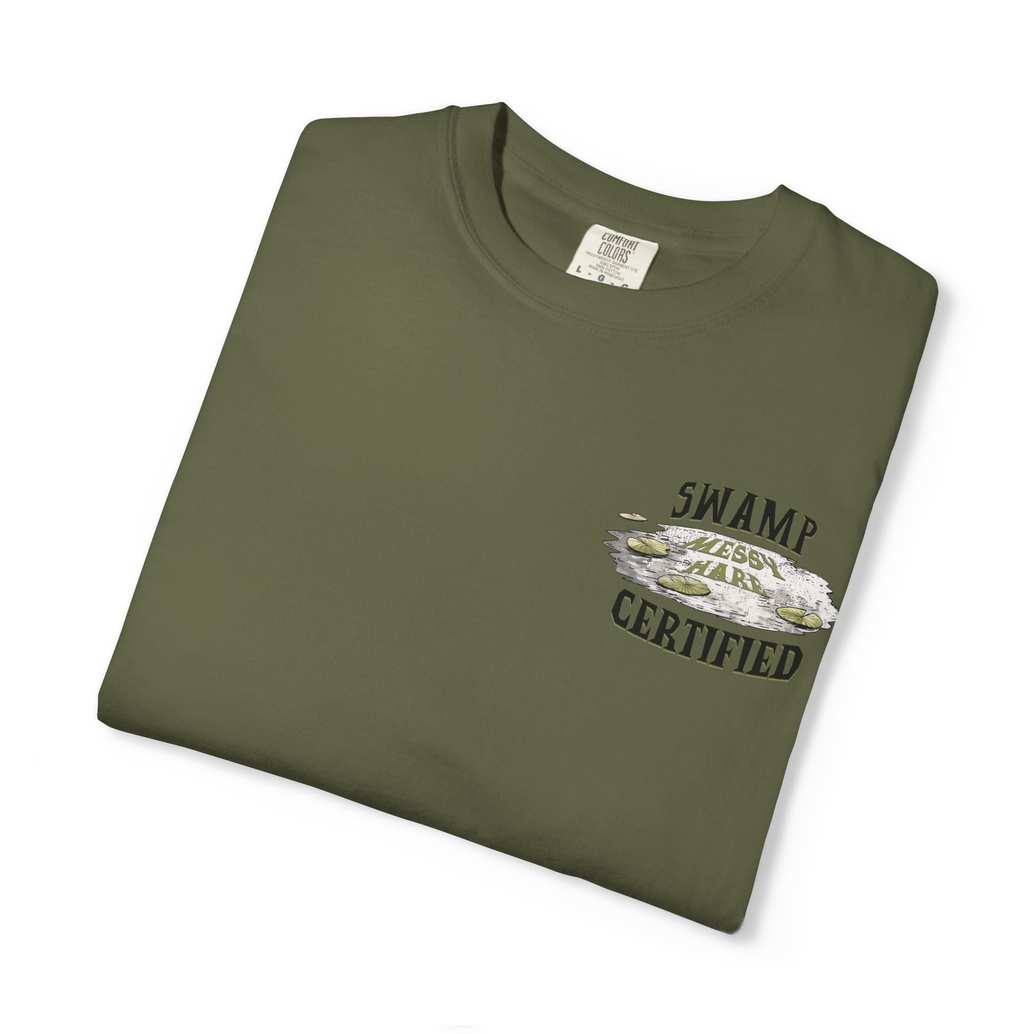 Folded green t-shirt with 'Swamp Messy Hair Certified' text and graphic on a white background