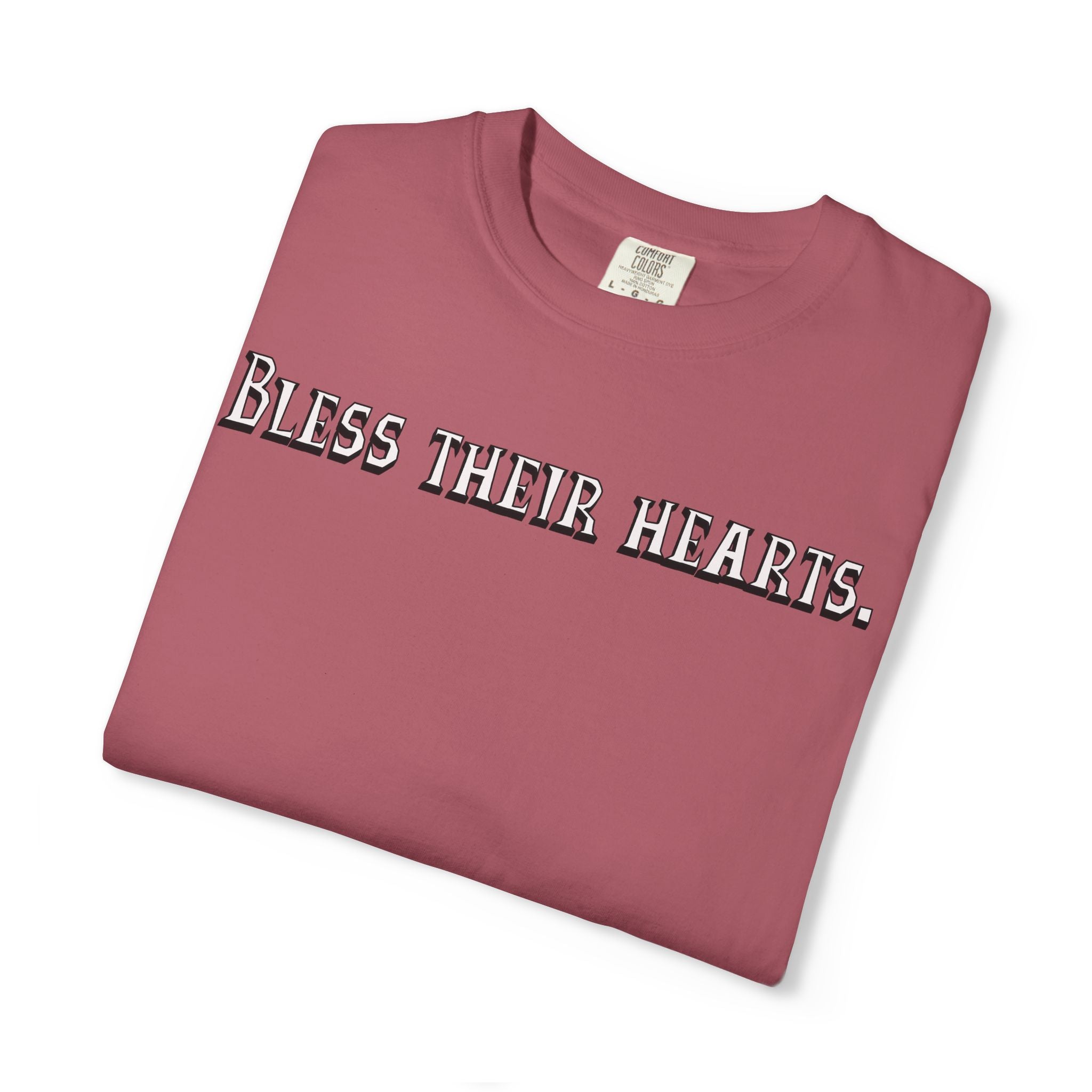 Folded maroon t-shirt with 'Bless their hearts.' text on a white background