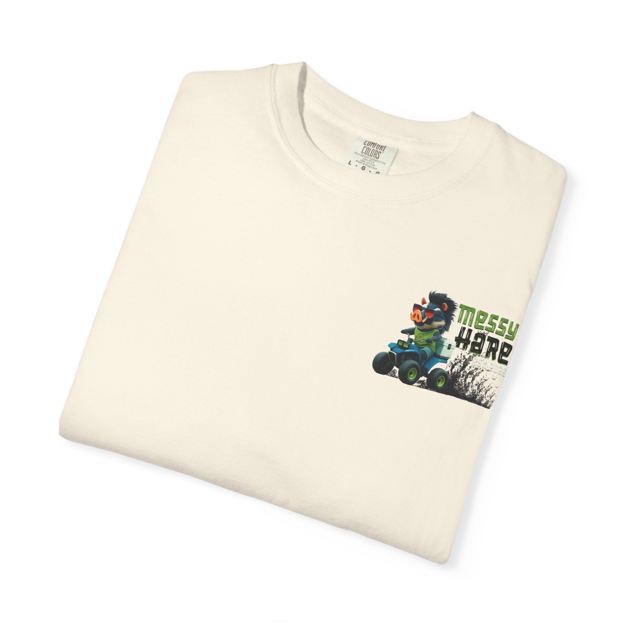 Folded cream-colored t-shirt with a graphic of a character on an atv and text 'Messy Here' on a white background.