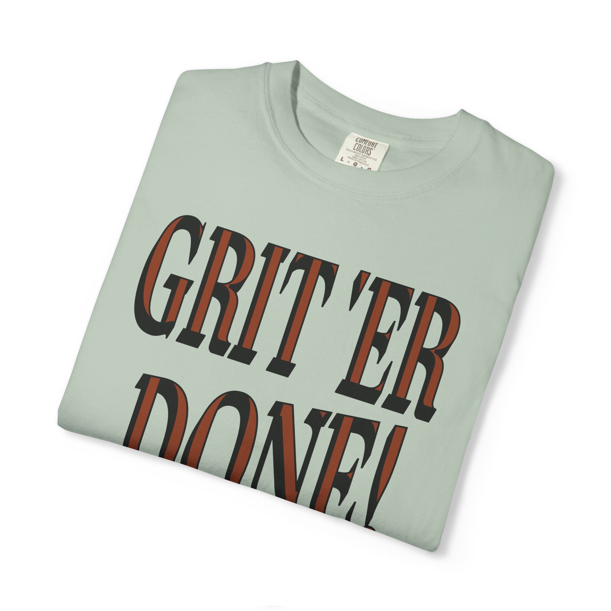 Folded light green t-shirt with 'GRIT'ER DONE!' text on a white background