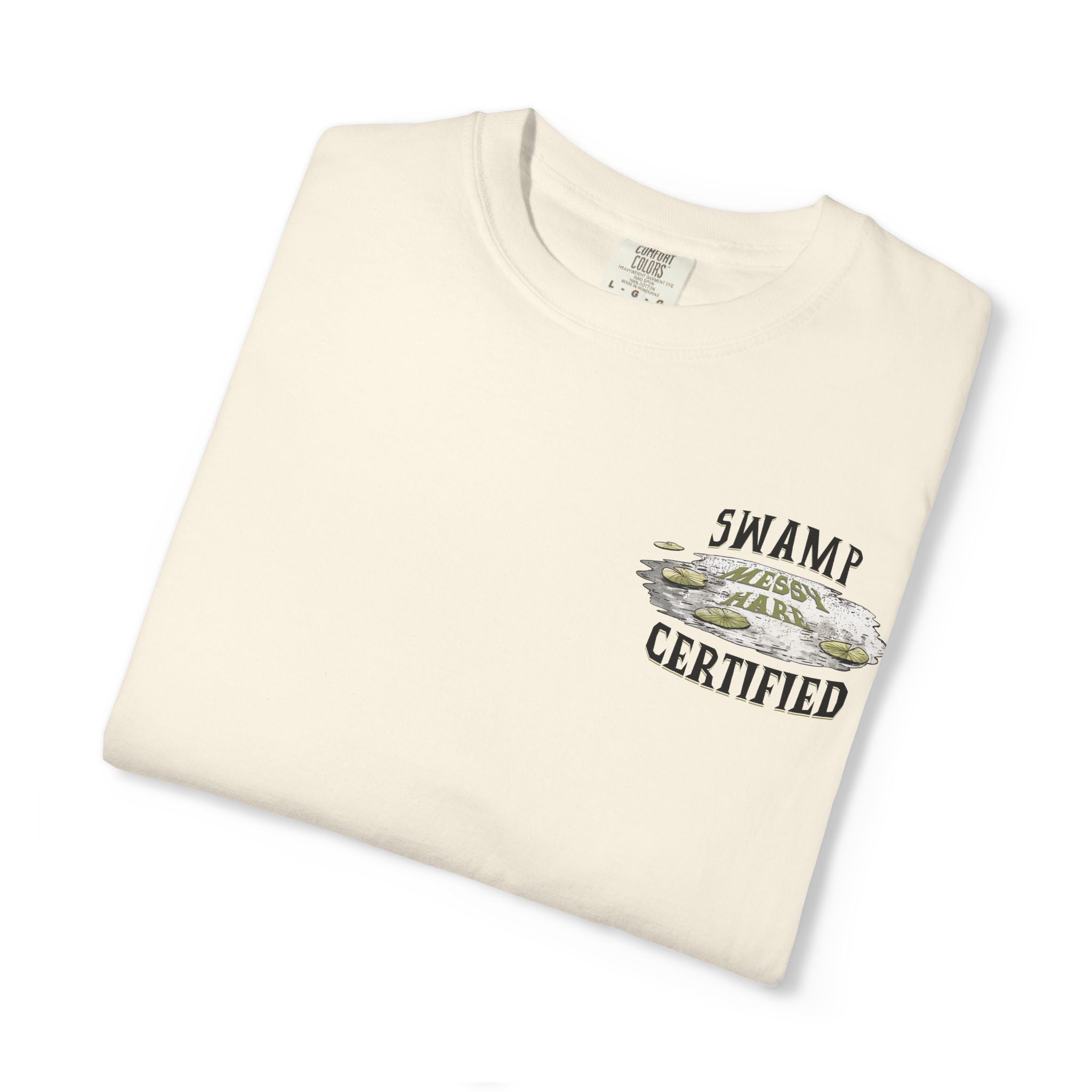 Folded cream-colored t-shirt with 'Swamp Certified' graphic on a white background