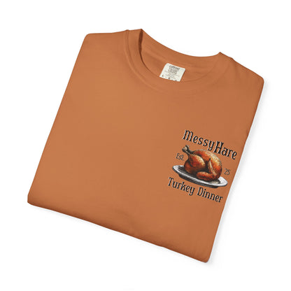 Folded brown t-shirt with 'Messy Hare Turkey Dinner' graphic on a white background