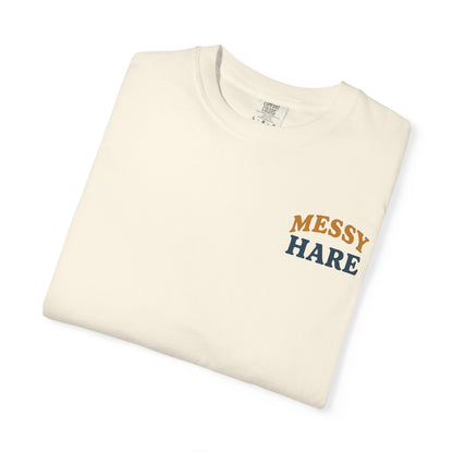 Folded cream-colored t-shirt with 'Messy Hare' text on a white background