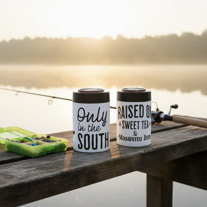 Two can holders with humorous text designs on a wooden dock by a lake.