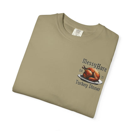 Folded khaki t-shirt with 'Messy Hare' and 'Turkey Dinner' graphic on a white background